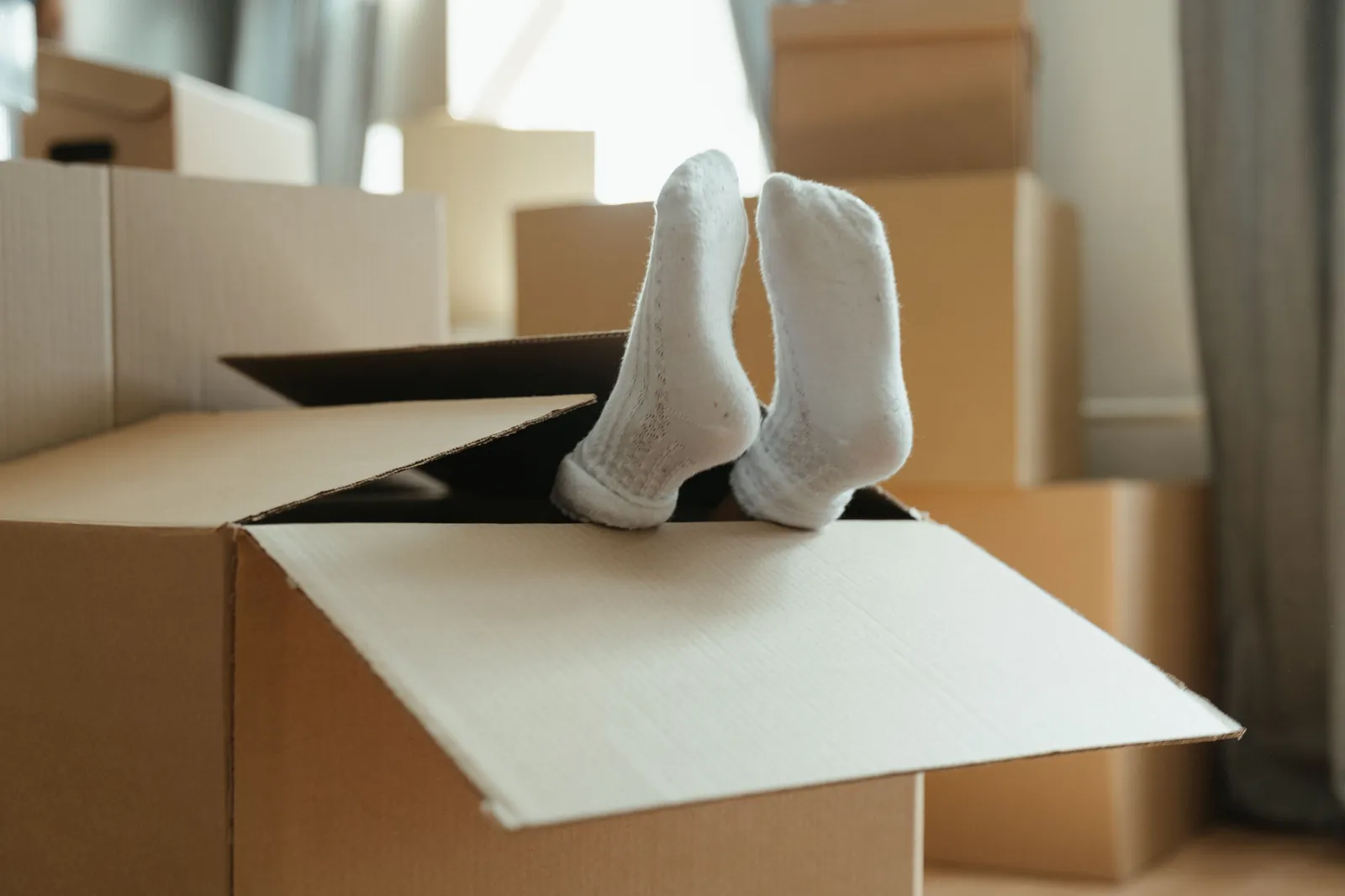 Person in weißen Socken entspannt sich mit den Füßen in einem offenen Umzugskarton